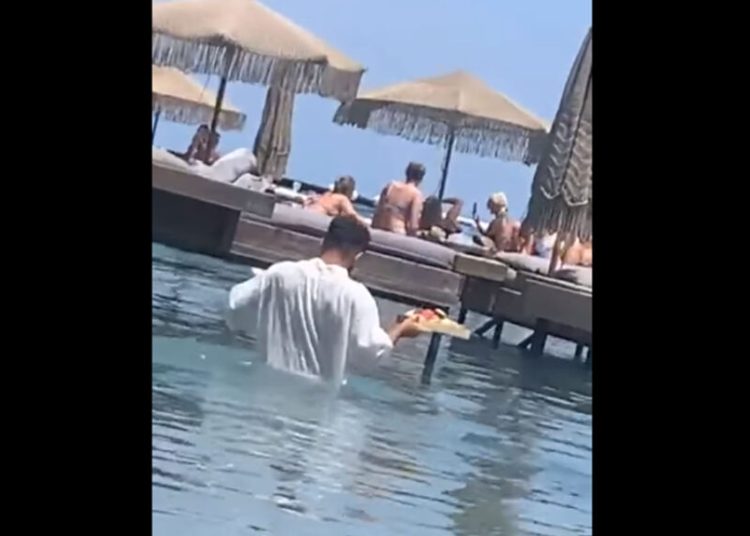 Ρόδος: «Δεν με ενοχλεί, παίρνω 200 ευρώ φιλοδώρημα», είπε ο σερβιτόρος που πήγε παραγγελία μέσα στη θάλασσα